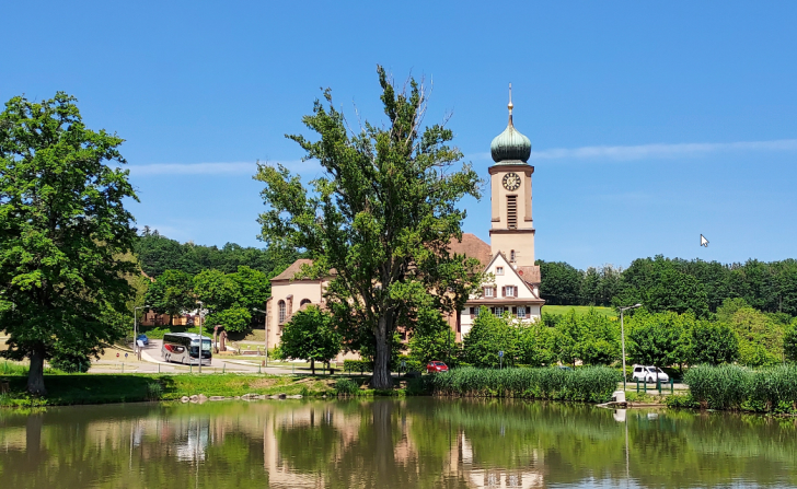 Vue sur le Sanctuaire Notre-Dame de Thierenbach entouré de verdure sous un ciel bleu